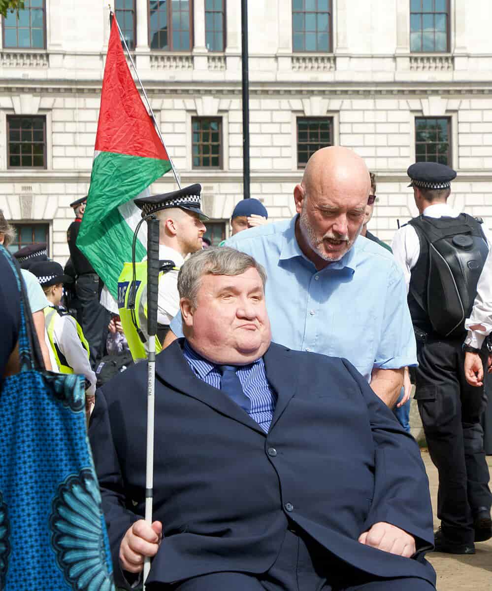 Mike Higgins, aged 62, who is blind and uses a wheelchair, was one of more than 1,600 people arrested since the UK's ban under the Terrorism Act came into effect on 5 July, mainly for holding signs reading 'I oppose genocide, I support Palestine Action'. Photo: Indigo Nolan/Flickr © CC BY 4.0