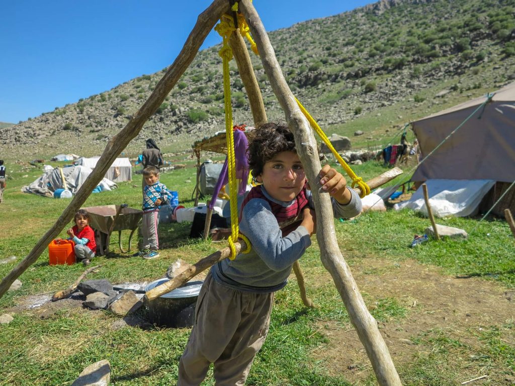 This is a photo of a young Kurdish boy hanging from a rod.