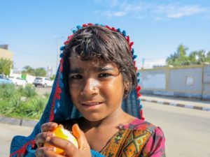 This is a photo of a young Baluchi girl holding an orange.