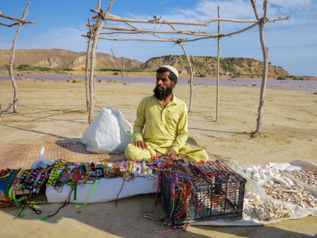 This is a photo of a Baluchi man selling colourful necklaces in the middle of desert.