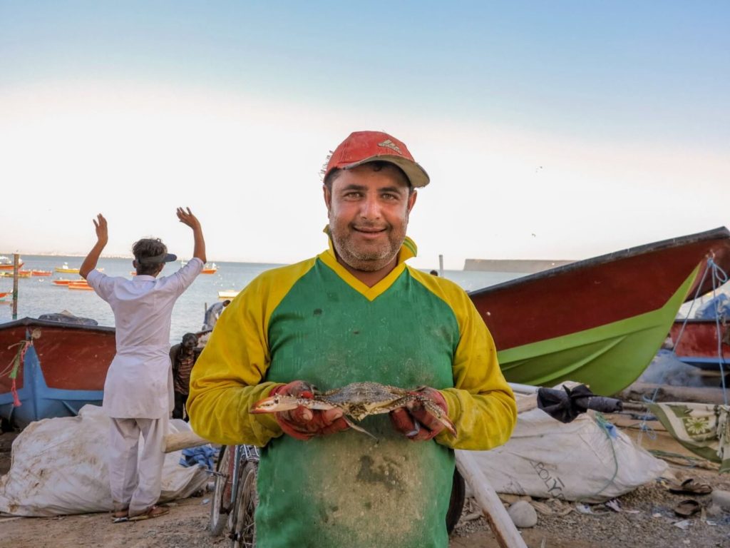 This is a photo of a Baluchi fisherman holding a crab.