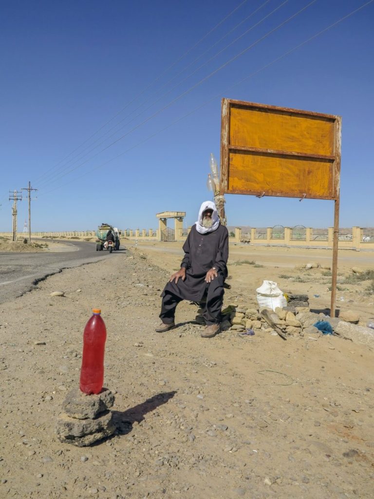 This is a photo of a man selling petrol in middle of a desert.
