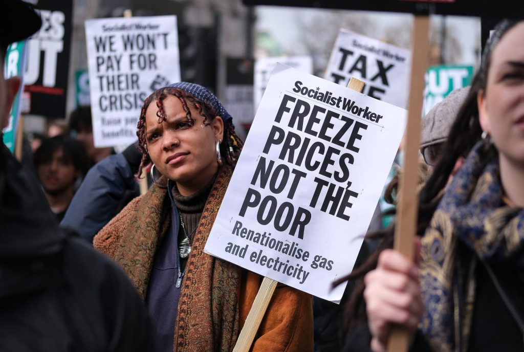 Women holding a sign that reads 'freeze prices, not the poor - rationalise gas and electricity' in RMT strike.