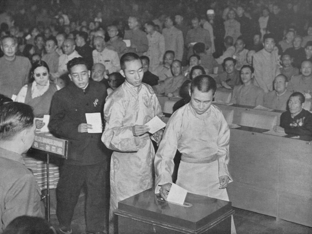At the first National People's Congress of the People's Republic of China, the Dalai Lama and Panchen Lama cast their votes for the Constitution amidst complex political pressures.